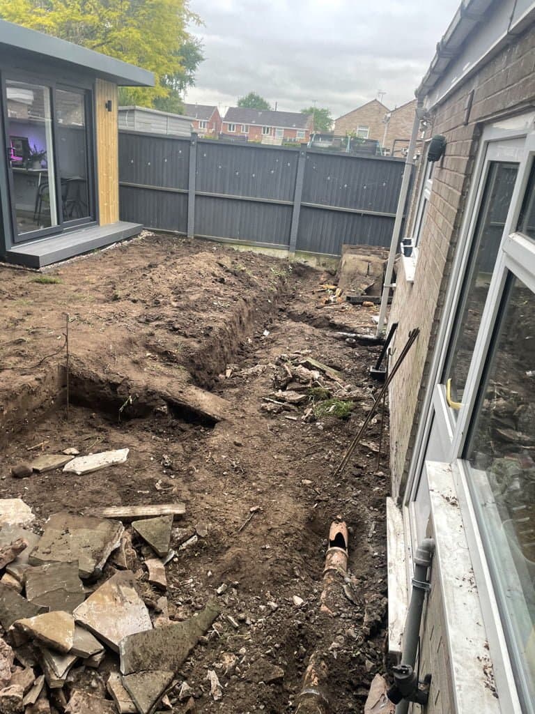 Groundworks under way for a new garden room and patio on Chestnut Drive, Congleton, with the black-clad structure already in place