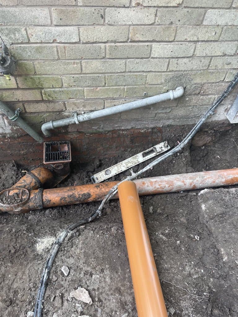 New drainage pipework connected at the base of a downpipe during groundworks in Congleton