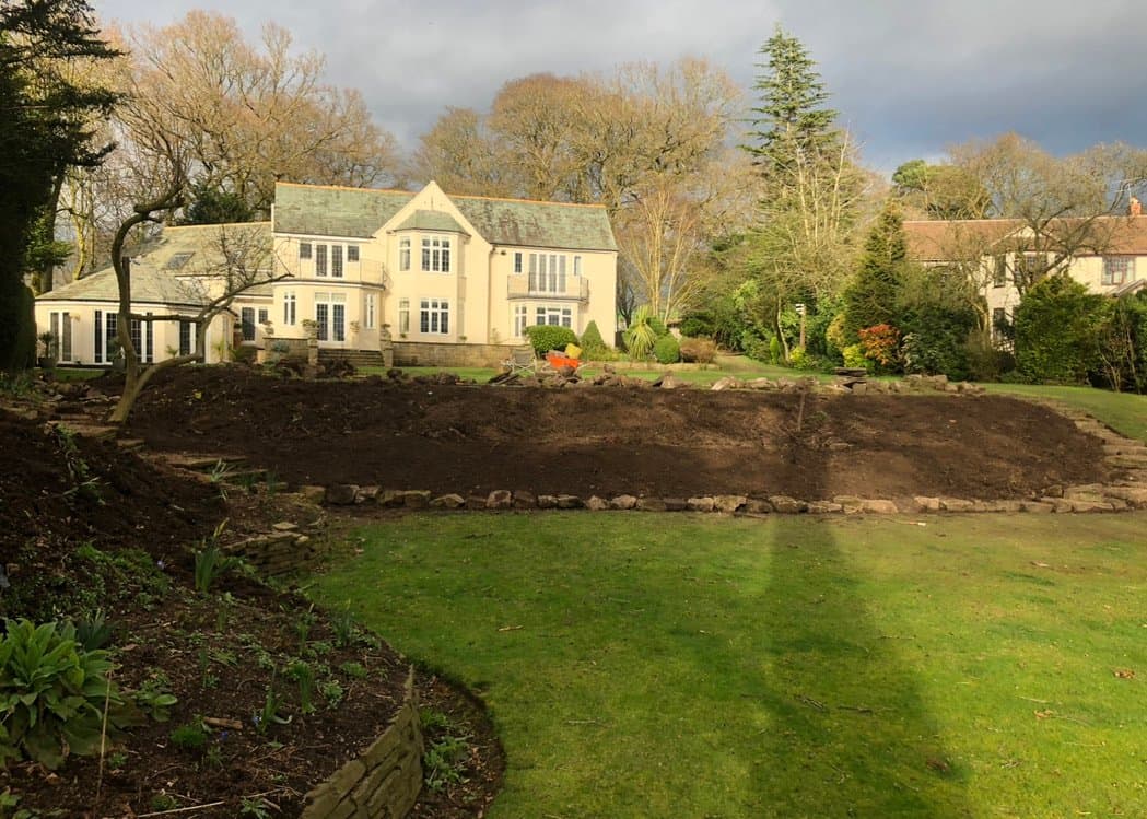 Raised soil bed edged in reclaimed stone at a grand Cheshire property during a garden transformation