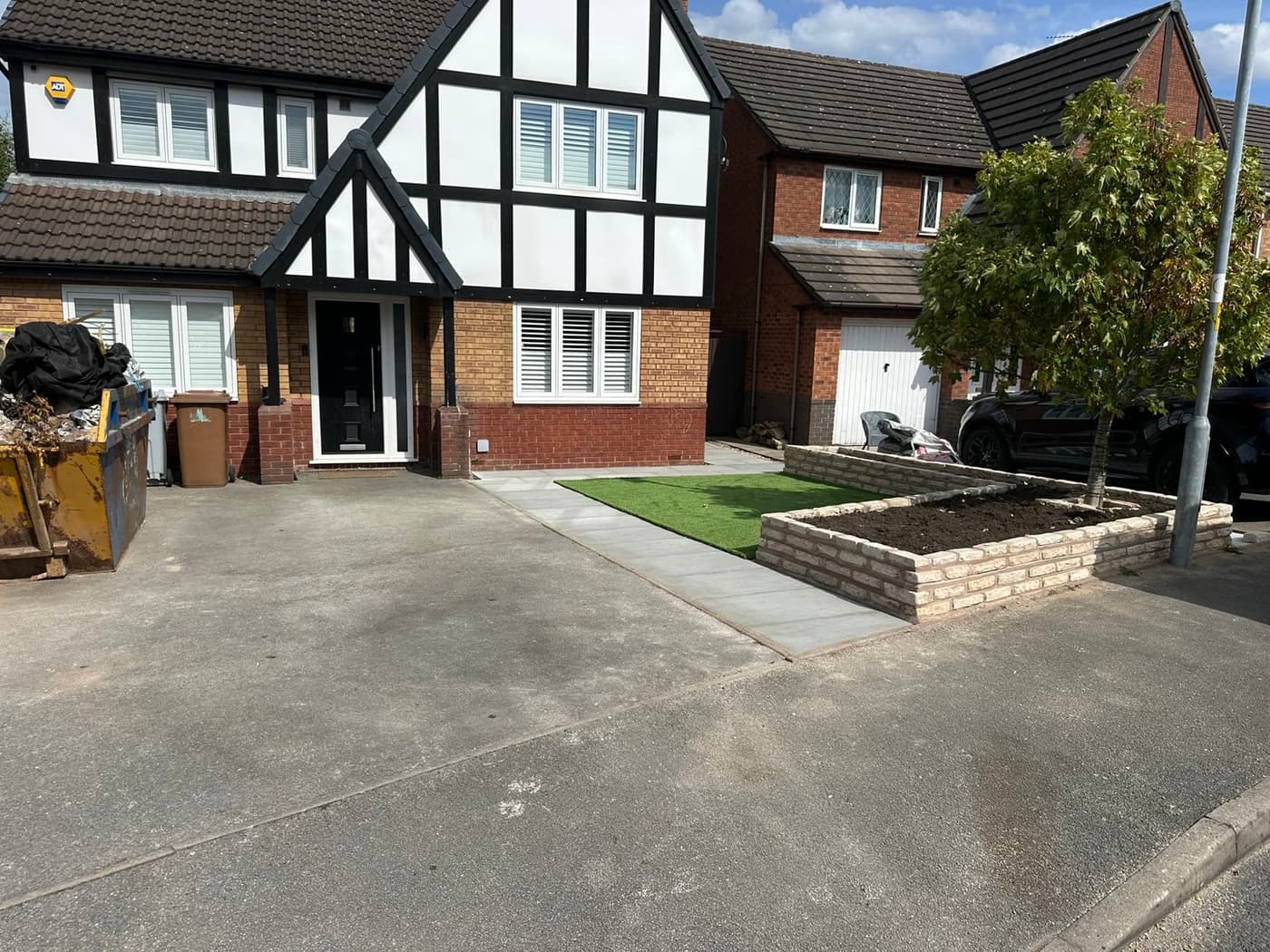 Raised planter built in matching fossil buff walling around a retained tree on White Park Close, Middlewich