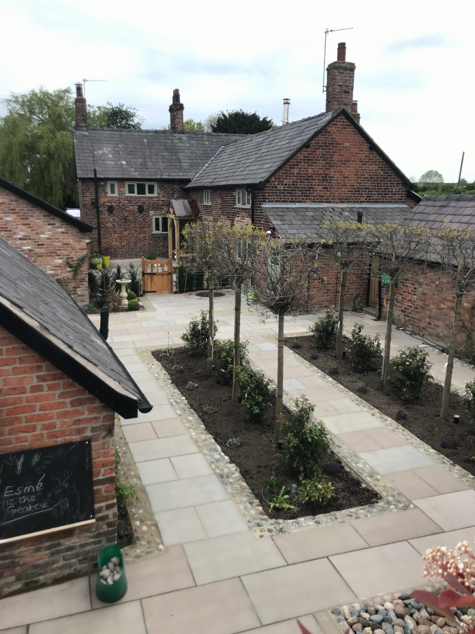 Formal courtyard garden with pleached trees and sandstone paving at a period farmhouse in Cheshire