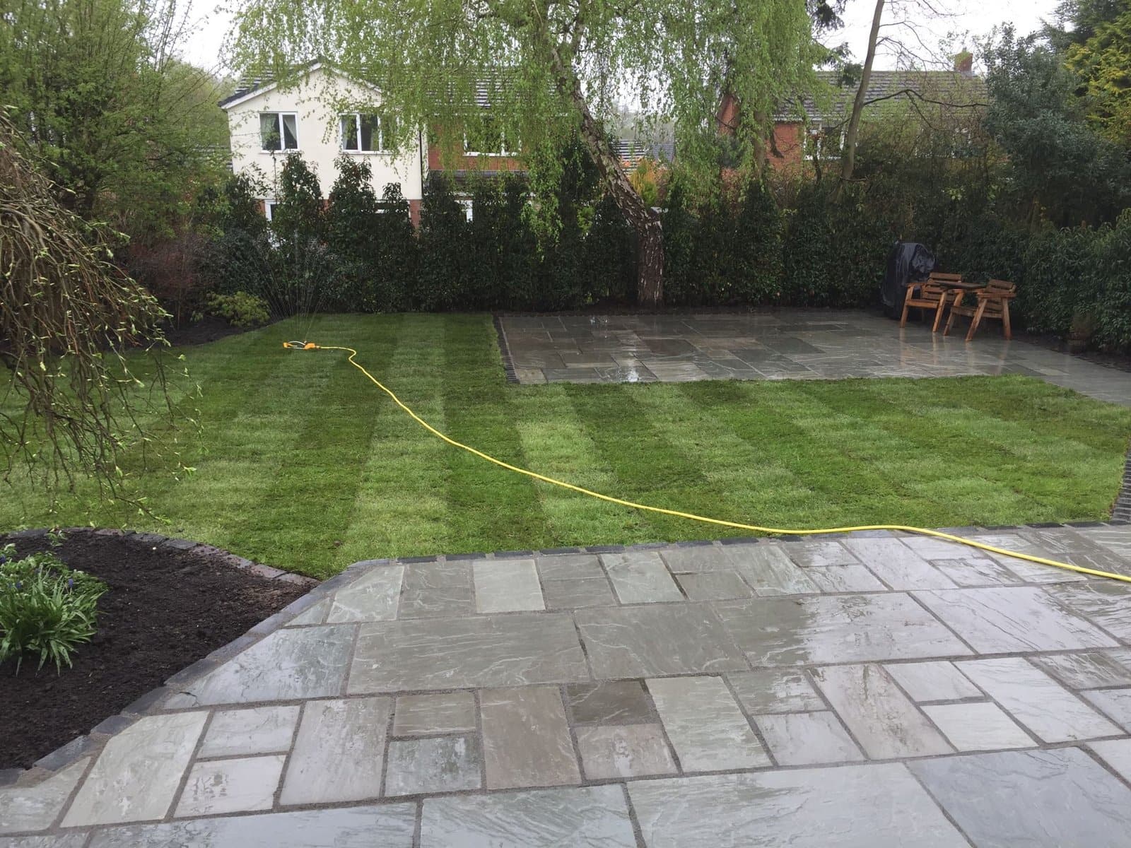 Indian sandstone patio beside a freshly striped lawn in Knutsford