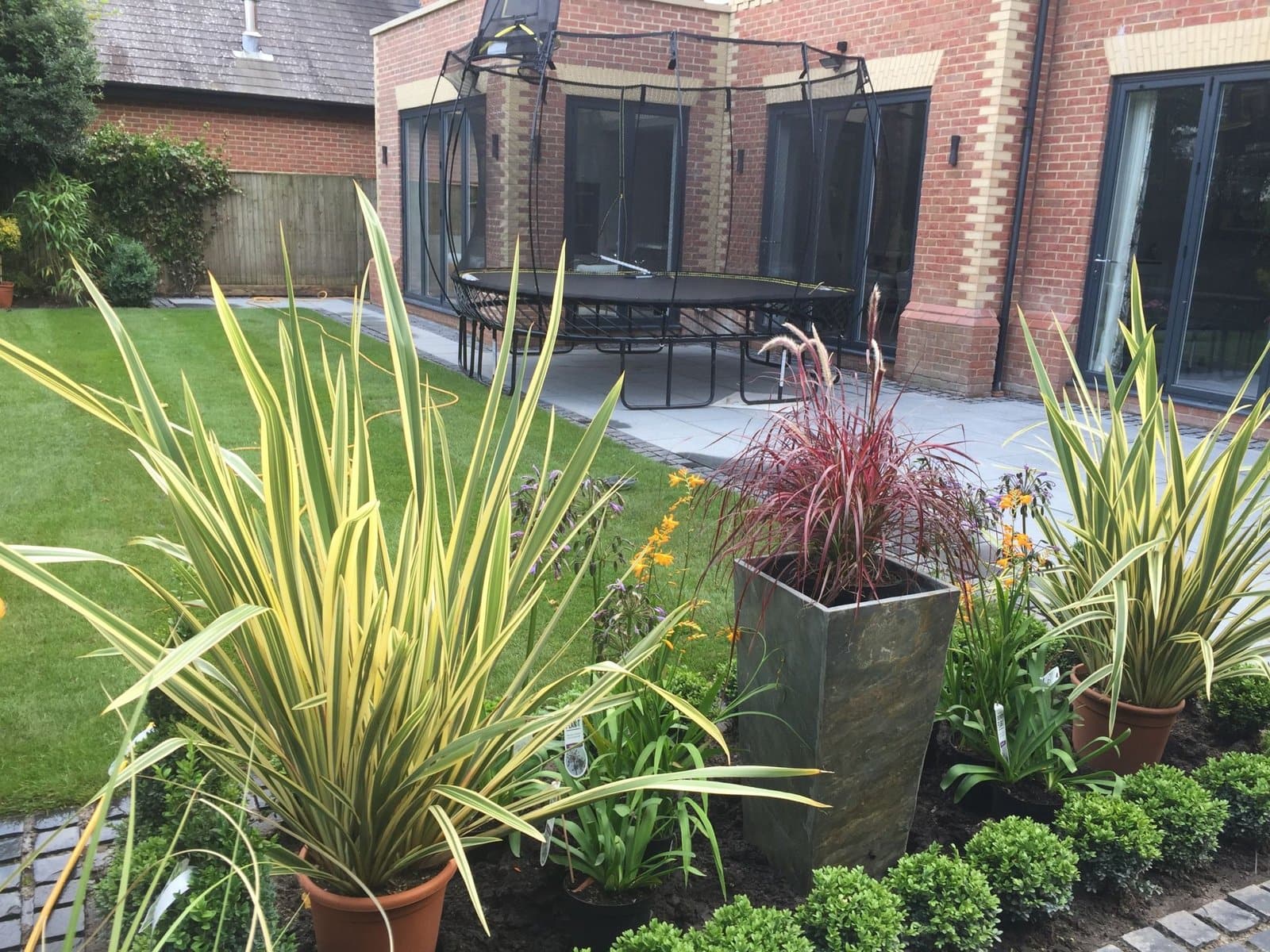 New garden border being planted with phormiums, grasses and a slate planter