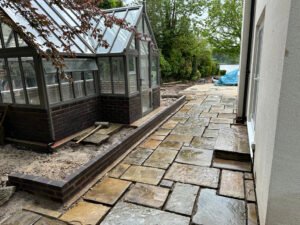 Completed sandstone terrace and brick detailing overlooking lakeside garden in Cheshire