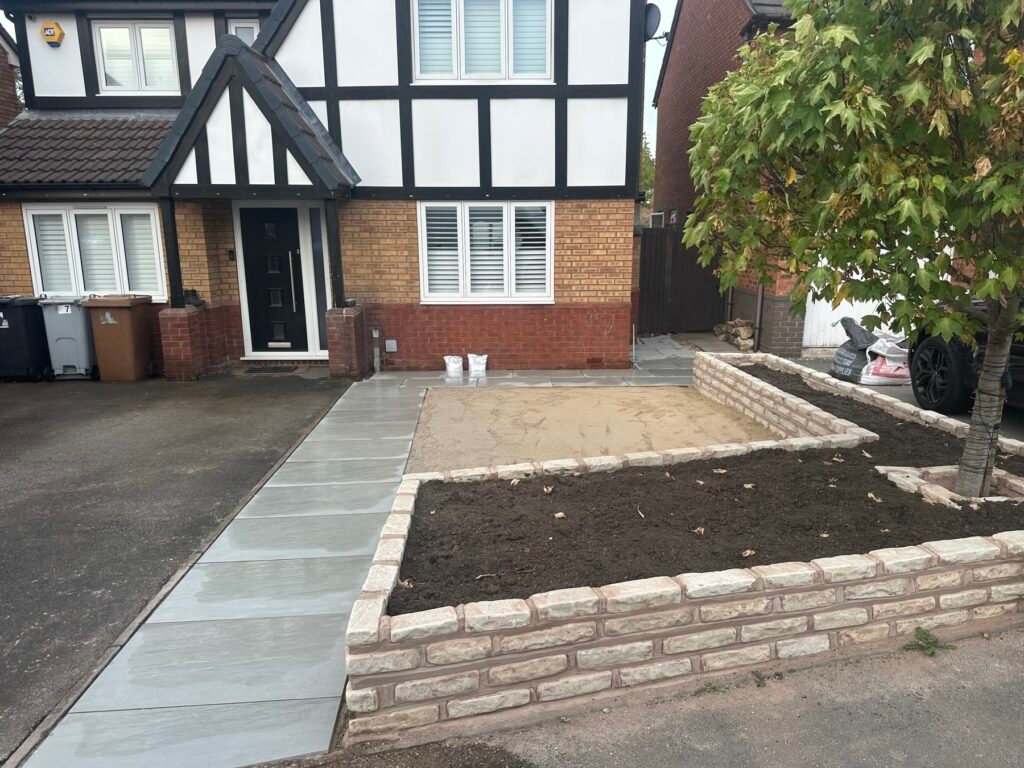 During the build: sandstone path laid, planter walls up, base prepared for the artificial lawn